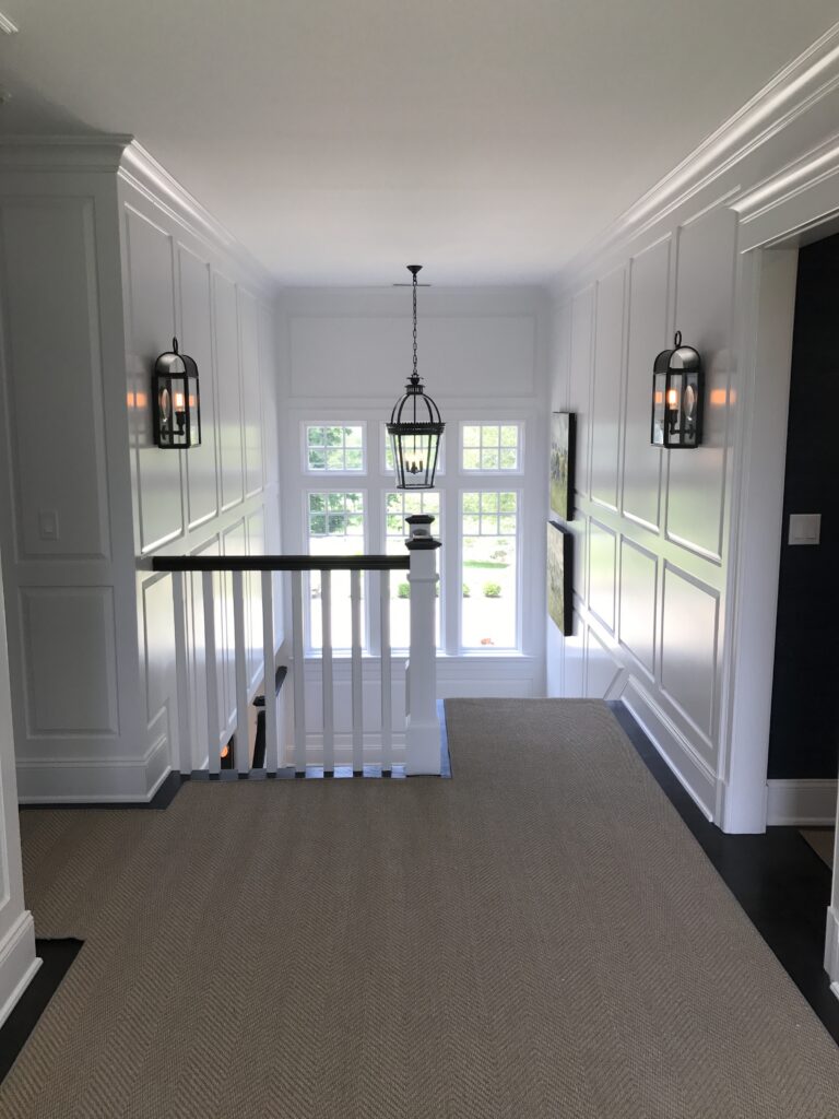 Interior painting project in Greenwich CT with bright white paneling and polished stair hall finish